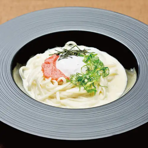 Mentaiko and shiso carbonara udon noodles with a soft-boiled egg.