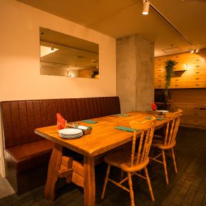 ソファ席はテーブル席と並ぶ形で配置されており、背もたれのある椅子でゆったりと座れるのが特徴。席の間隔が保たれており、2名～4名での利用に適しています。落ち着いた照明と木目調の床が調和し、会話を楽しみたい食事シーンにぴったりです。店全体のナチュラルな雰囲気に馴染む、リラックスしやすい空間です。