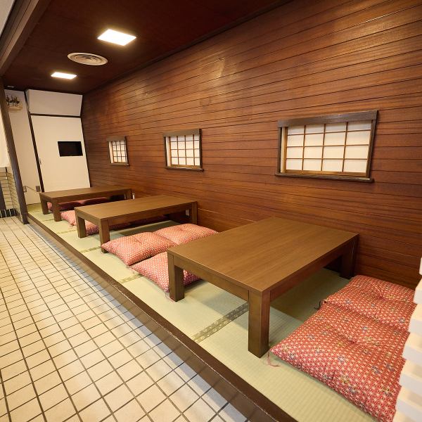 畳敷きの小上がり席には、可愛らしい和柄の座布団が並び、靴を脱いでくつろげる安心感のある雰囲気。木目調の壁面と障子風の窓が懐かしさと癒しを演出し、まるで自宅にいるようなリラックス空間を提供します。ご家族やお子様連れにもおすすめです。