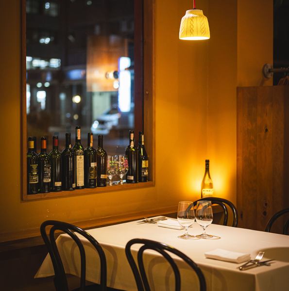 窓際のテーブル席。ほのかに灯りをともすワインボトルで作られた優しい照明を眺めながらお食事できます。ご家族でのお食事、デートなどにピッタリのお席です。