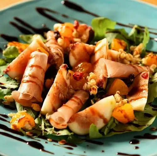 Caprese salad with seasonal fruits, prosciutto, and mozzarella.