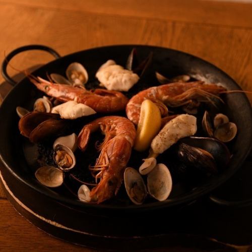 我们著名的海鲜饭装在易于食用的墨鱼汁海鲜饭中，可供 2 至 3 人食用