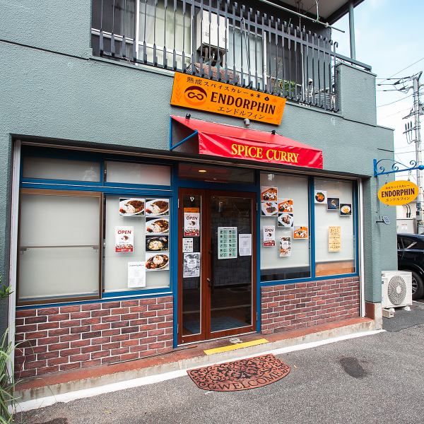 高島平駅から徒歩3分の当店は、レンガ造りの建物と赤い暖簾が目印です。店内にはカレーのスパイシーな香りが広がり、食欲をそそります。新感覚の美味しいカレーを楽しむために、ぜひお越しください。一度来たらやみつきになること間違いなし！お待ちしております！