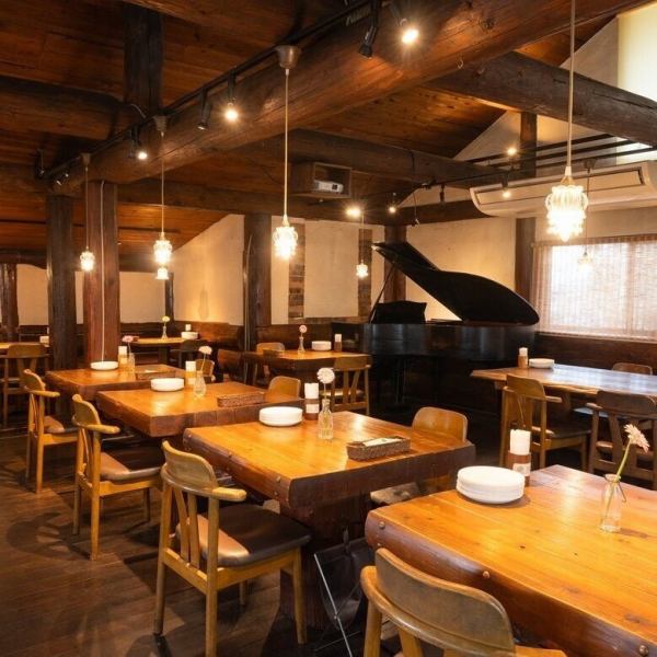 木の温もりと高い天井が生み出す開放感に包まれる空間。ログハウスならではの落ち着きの中に、やわらかく灯るシャンデリアが調和します。中央にはグランドピアノが佇み、木のぬくもりが特別なひとときを優雅に彩ります。