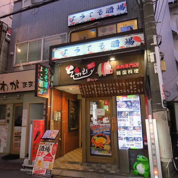 木目調の温かみある外観が目印の韓国料理店。豚肉専門店ならではの存在感ある看板と、明るく見やすいメニュー看板が店頭を彩ります。入口は入りやすい雰囲気で、おひとり様からグループ利用まで気軽に来店可能。駅近の立地で仕事帰りや飲み会、食事利用にも便利な、親しみやすく活気あふれるお店です。