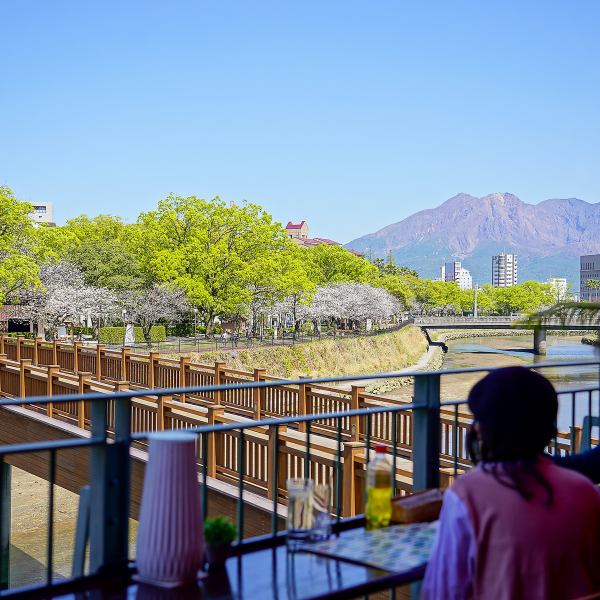 位於Kotsuki河沿岸，我們設有可欣賞櫻島景色的開放式露台座位。一邊欣賞四季風光，一邊悠閒地用餐。