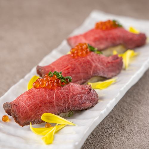 Three pieces of beef tataki nigiri sushi with salmon roe