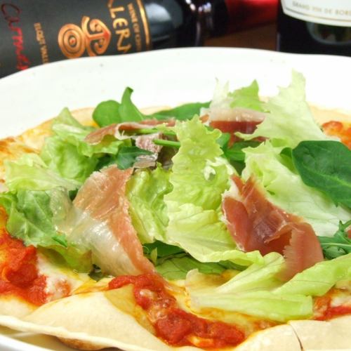 Pizza with prosciutto and raw vegetables