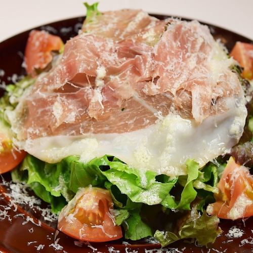 Caesar salad topped with prosciutto