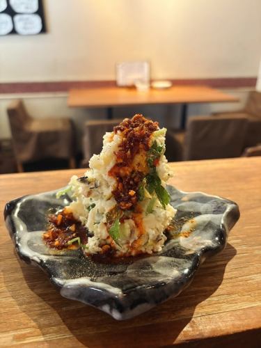 【ブルディルマーレ】
薬味たっぷりポテトサラダ
〜自家製食べるラー油がけ（グリルネギと三つ葉入り）〜

ホクホクのじゃがいもに、香り高いグリルしたネギとさわやかな三つ葉を加えた、和風仕立てのポテトサラダです。たっぷりの薬味を合わせて、さっぱりとした風味と食感のアクセントをプラス。仕上げに、自家製の「食べるラー油」をたっぷりとかけて、ピリッと香ばしい旨辛さを添えました。食欲をそそる味わいで、おつまみにもぴったりの一皿です。

📍広島市中区立町6-1 ウイングビル1階　0822490007 ◆広島レモンを使った最強レモンサワー ◆ぷりぷり広島牡蠣を堪能。 ◆昼から飲める 路面店で、気軽に立ち寄れる洋食レストラン。 ✴︎営業時間✴︎ 火曜〜金曜15時〜21時半ラストオーダー 土曜日曜日12時〜21時半ラストオーダー 月曜日定休日+不定休有 ご予約0822490007  web予約 https://buldelmare.owst.jp/ #広島グルメ  #広島レストラン #広島ランチ  #広島観光  #hiroshima #レストラン