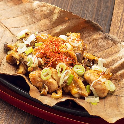 Chicken shoulder and two kinds of mushrooms grilled on a magnolia leaf