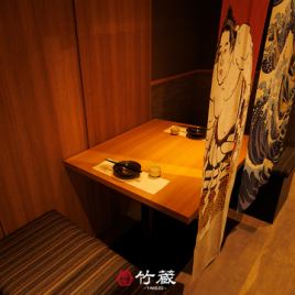［2名様：半個室］柔らかな灯りに包まれた二人掛けの上質な半個室。木の温もりと和の意匠が交わる静謐な設え。和柄の仕切りが程よい距離感を演出し、親密な会話や特別なひとときを優雅に包み込みます。