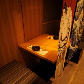 ［2名様：半個室］柔らかな灯りに包まれた二人掛けの上質な半個室。木の温もりと和の意匠が交わる静謐な設え。和柄の仕切りが程よい距離感を演出し、親密な会話や特別なひとときを優雅に包み込みます。