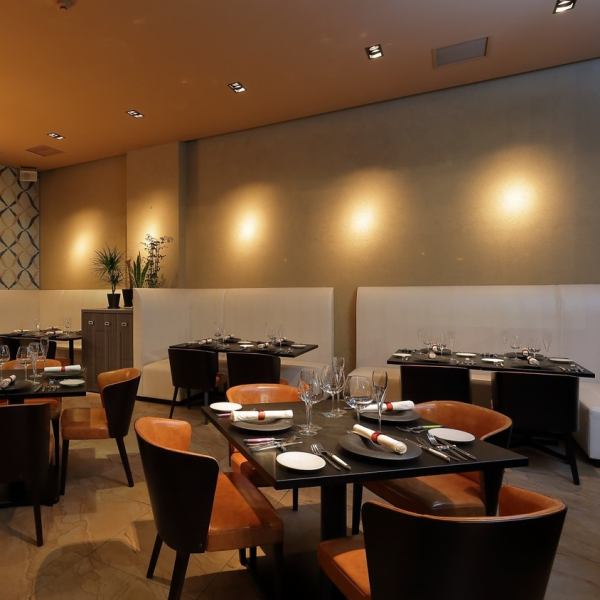 【テーブル席】店内は洗練された高級感あふれる雰囲気で、大人デートにもぴったりな空間です。恋人同士で肩と肩を並べて座れば、ゆっくり会話とお食事をお楽しみいただけます。その他、おひとり様、女子会、記念日、誕生日、パーティー、二次会など様々なシーンでお使いいただけます。どなた様もお気軽にご来店ください。