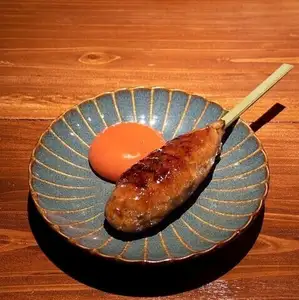Chicken meatballs on a skewer with sauce and egg.