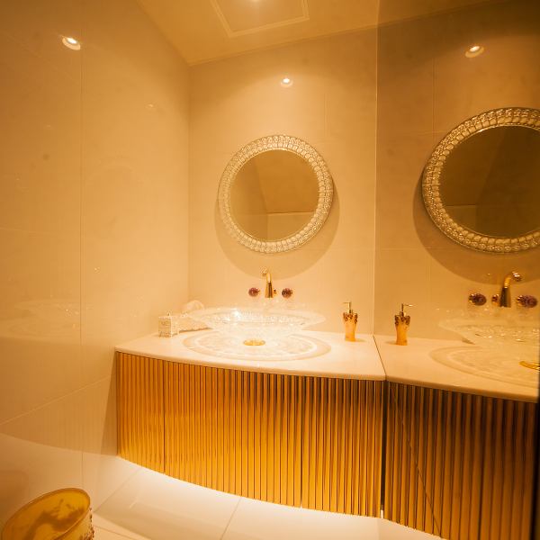 【日本初】パウダールームには、クリスタルガラスに豪華に彫刻された宝石のような洗面ボウルとミラーが。 花の形をした蛇口に、ノブはアメジストが使われています。壁と床面にはチャペルでも使用する特殊なガラスコーティングされたタイルを使用しています。 右側の壁面にはブロンズミラーが貼られています。 