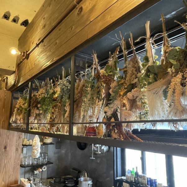 当店の店内は、ドライフラワーが吊るされたオシャレな空間で、自然を感じながらお食事を楽しめます。ハンドメイドの内装が心地よい緑の空間を演出しており、リラックスしたひとときを提供します。