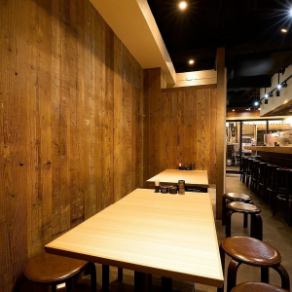 【1階テーブル席：2～8名様】調理の音や香りを感じながら少人数宴会をするならこちら。調理場の豚巻き野菜串や鉄板焼きが焼ける音・香りなどを感じつつも、少し奥まった場所にあるため落ち着いて過ごせるお席です。木目調のインテリアや内装が心地よく、大切な方とのデートや女子会、同僚との飲み会に最適！