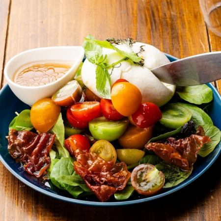 Caprese with colorful tomatoes and melted Italian burrata cheese