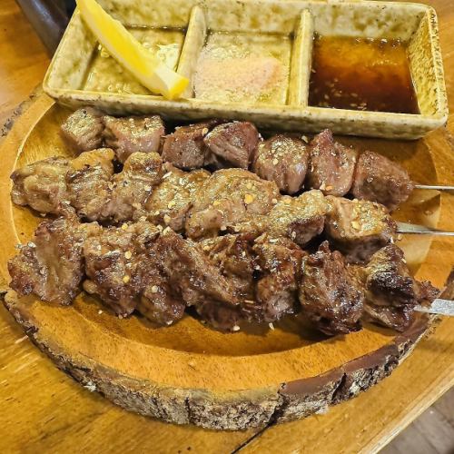 3 pieces of beef skewers on a log