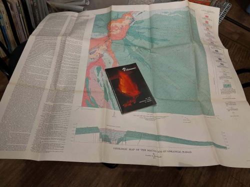 今夜、お客様から1971年発行の
ハワイ・キラウエア火山の地質図と冊子をいただいた。

広げると、紙の上に流れた溶岩の時間が、そのまま定着している。
色分けされた地層、等高線、噴火の履歴。
これは「景色」ではなく、「地球の記憶」そのものだ。

1971年。
まだGPSもなく、衛星写真も今ほど手軽ではない時代。
人が歩き、測り、考え、積み重ねて描かれたマウナ・ロアとキラウエアの姿。
折り目ひとつひとつに、フィールドに立った研究者の体温が残っている気がする。

添えられていた冊子
『Volcanoes of the National Parks in Hawaii』。
火山は「観光資源」である前に、
生きて動く大地そのものだという、静かな覚悟がページから伝わってくる。

地図は未来を当てるための道具ではない。
地図は「過去が、どうやって今になったか」を教えてくれるものだと思う。

この地図が描かれた1971年から半世紀。
キラウエアは何度も噴火し、姿を変え、
それでも火山であり続けている。

人も、街も、店も、たぶん同じだ。
積み重なった時間の上に、いま立っている。

こういう一枚が、ふっと現れるから
地図カフェはやめられない。

大切に、店のどこかに広げておきます。
ぜひ、紙の上のハワイを旅しに来てください。

#地図カフェ
#地質図
#キラウエア火山
#ハワイ
#1971年
#地図のある風景
#紙の地図
#地球の記憶
#MapsMatter