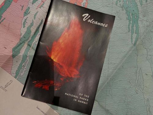 今夜、お客様から1971年発行の
ハワイ・キラウエア火山の地質図と冊子をいただいた。

広げると、紙の上に流れた溶岩の時間が、そのまま定着している。
色分けされた地層、等高線、噴火の履歴。
これは「景色」ではなく、「地球の記憶」そのものだ。

1971年。
まだGPSもなく、衛星写真も今ほど手軽ではない時代。
人が歩き、測り、考え、積み重ねて描かれたマウナ・ロアとキラウエアの姿。
折り目ひとつひとつに、フィールドに立った研究者の体温が残っている気がする。

添えられていた冊子
『Volcanoes of the National Parks in Hawaii』。
火山は「観光資源」である前に、
生きて動く大地そのものだという、静かな覚悟がページから伝わってくる。

地図は未来を当てるための道具ではない。
地図は「過去が、どうやって今になったか」を教えてくれるものだと思う。

この地図が描かれた1971年から半世紀。
キラウエアは何度も噴火し、姿を変え、
それでも火山であり続けている。

人も、街も、店も、たぶん同じだ。
積み重なった時間の上に、いま立っている。

こういう一枚が、ふっと現れるから
地図カフェはやめられない。

大切に、店のどこかに広げておきます。
ぜひ、紙の上のハワイを旅しに来てください。

#地図カフェ
#地質図
#キラウエア火山
#ハワイ
#1971年
#地図のある風景
#紙の地図
#地球の記憶
#MapsMatter