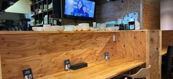 木の温もりを感じるカウンター席が並ぶ落ち着いた店内。オープンキッチンの向こうには、料理を待つ器が整然と並び、ライブ感のある雰囲気を演出。壁には大型テレビが設置され、韓国ドラマやK-POP映像を楽しみながら食事ができるのも魅力。カウンター席は一人でも気軽に利用でき、ゆっくりと食事を楽しめる空間。