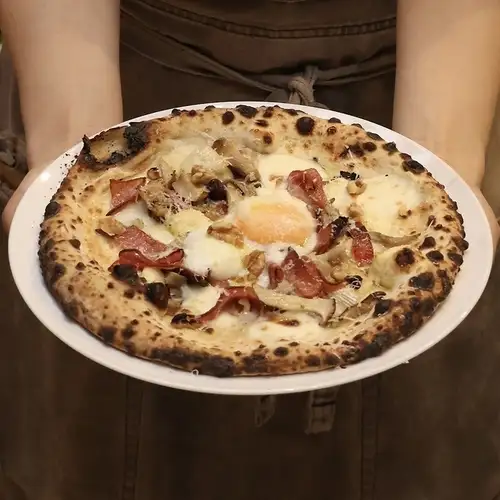 Pizza with porcini cream, walnuts, mortadella, salami, and a soft-boiled egg.