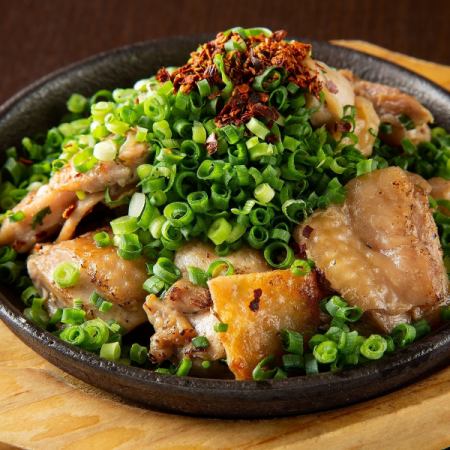 Chicken covered in green onion on iron plate