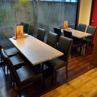 【照明を眺めながら壁際でくつろぐテーブル席：2名様～6名様】店内奥には大きな窓際のテーブル席を設置。4名様用を1卓、6名様用を1卓ご用意いたしました。2名様よりご利用いただけます。外が暗くなると庭の照明が灯り、ムーディーな雰囲気に。おしゃべりをゆっくり楽しむ女子会に、デートや記念日になどにおすすめです。