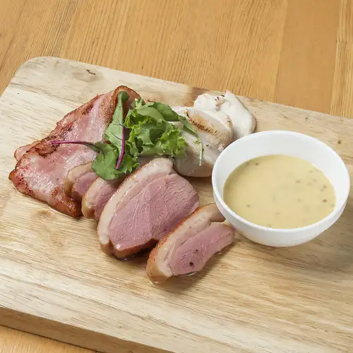 A platter featuring two types of charcoal-infused bacon and smoked chicken.