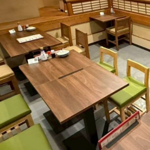 テーブル席は、緑と茶色を基調とした和の落ち着きある雰囲気が特徴で、店外に置かれた植物を見ながらお食事も楽しめ、自然の温かみを感じられる空間が広がっています。ゆったりと座れるため、ご友人同士の食事やご家族での利用にも最適。リラックスしてお食事を楽しめる心地よい時間を演出します。