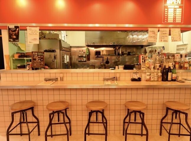 当店は、懐かしさを感じさせる古き良きダイナーの雰囲気を大切にしています。大人の遊び心がくすぐられる色合いのインテリアや、温かい照明に包まれた空間は、まさに大人の集い場。お酒を楽しむ仲間たちが集い、笑い声が響く場所で、特別なひとときをお過ごしください。