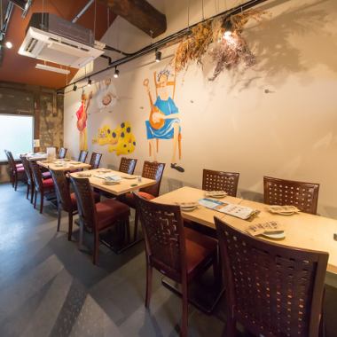【テーブル席】壁のユニークなイラストが目を引くテーブル席は、女子会や友人同士の食事に最適。気軽に賑やかなひとときを過ごせます！