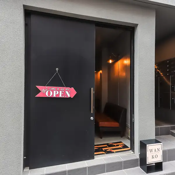閑静な住宅街にひっそりと佇む当店。グレーの壁とスタイリッシュな黒い扉、そして目を惹く赤い「OPEN」の看板が目印です。一歩足を踏み入れれば、日常の喧騒から離れた大人の隠れ家空間が広がります。ご友人との語らいから、20名様までの貸切宴会まで、上質な料理と美酒に酔いしれる至高の夜をお約束いたします。