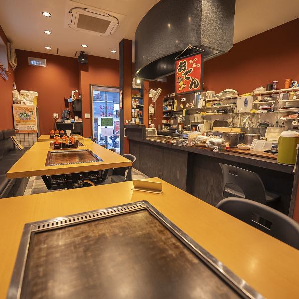 赤みがかった壁と木の質感が調和した和モダンな空間。鉄板付きのテーブルが並ぶ店内は、どこか懐かしさを感じさせながらも洗練された雰囲気。4名掛けのテーブル席はゆったりと配置されており、落ち着いて食事を楽しめます。温かな照明が心を和ませ、居心地の良さも抜群です。