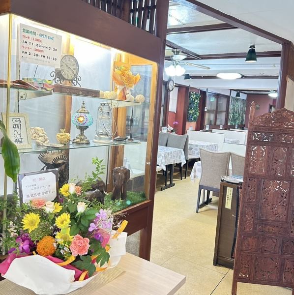 入口前のショーケースには、インドを感じさせる色鮮やかな置物たちがお出迎え。小さなガネーシャ像や伝統的な民芸品が並び、まるで異国の文化に触れるようなひとときを演出しています。お店に入る前から、インドの温かさとスパイスの香りが感じられるような、そんな特別な入口です。