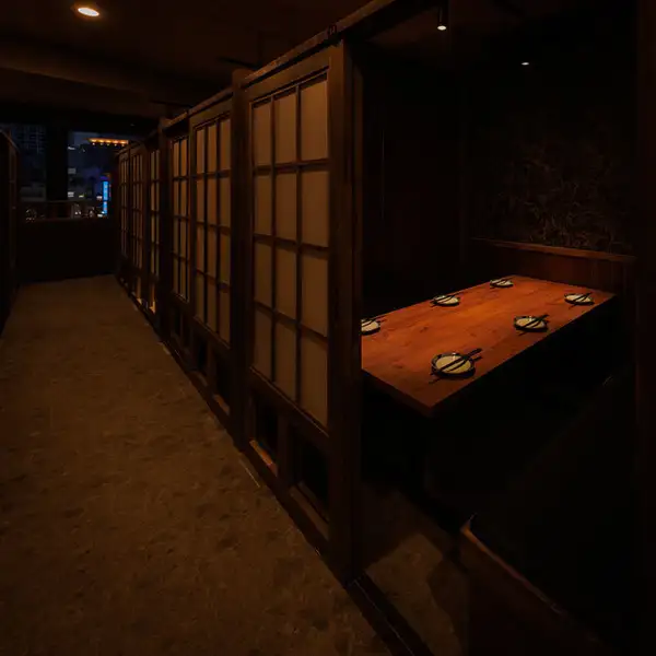 木格子の引き戸が並ぶ、しっとり落ち着いた店内。通路から一歩入ると、木の温もりとやわらかな灯りに包まれる個室空間が広がります。飲み会や会社帰りの一杯、ゆっくり語りた食事にもぴったりです。