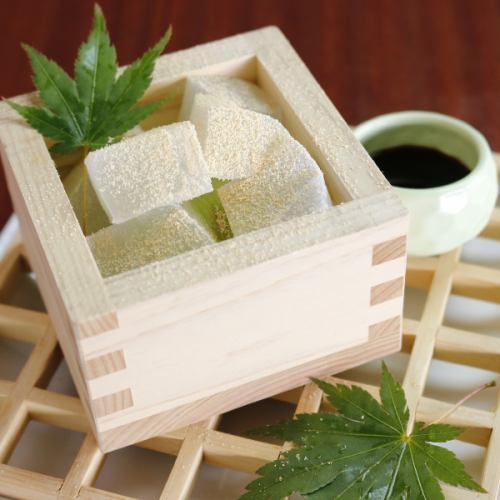 Warabimochi and matcha ice cream served in a wooden box with brown sugar syrup