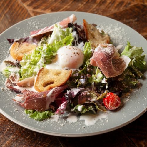 Caesar salad with raw ham and warm egg