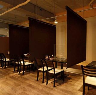 壁に面したテーブル席が全4卓。ロールカーテンで仕切られたお席3卓は、つなげて最大12名様までのご利用も可能。感染防止のため、お一人様分のスペースごとにアクリル板を設置しております。