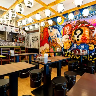 【当日予約OK】博多中洲屋台村 なんしょっと？を象徴する『巨大壁絵』を眺めながら臨場感ある宴会や飲み会などに抜群のテーブル席となっております。店内にはTVモニターも完備しておりスポーツ観戦にも最適な空間となっております！デートや誕生日会、普段の飲み会から大人数の宴会まで幅広くご利用いただけます♪