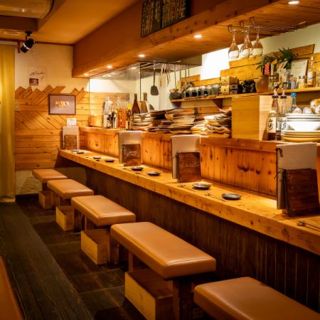 温かい照明が灯るカウンター席。目の前には信楽焼きのお皿や種類豊富なお酒を並べており、テーブル席とは違った楽しみ方ができます。