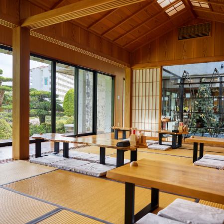 天井まで続く木の質感と、一面の窓から差し込む光が心地よい座敷空間。4名掛け・6名掛けを各3席ずつ備え、大人数でもゆったり過ごせる広さが自慢です。畳に座って目線の高さで楽しむ庭園の緑は、まさに格別。開放感あふれる和の特等席で、日常を忘れる贅沢なひとときをお過ごしください。