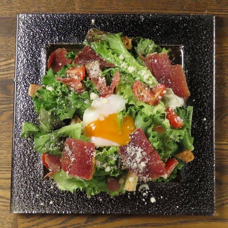 Prosciutto Caesar salad topped with a soft-boiled egg