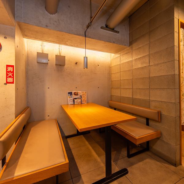 コンクリート壁と木のテーブルが調和するテーブル席は、静かで落ち着いた雰囲気。少人数での食事や女子会にぴったりな空間で、周囲を気にせずゆったりと過ごせます。温かみとプライベート感を両立した設えです。