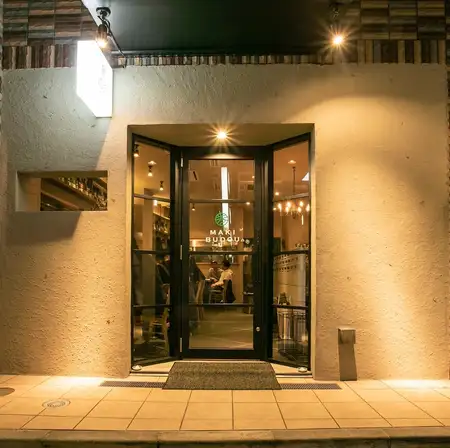 窓からのぞくにぎやかな店内。テーブルには創作串と国産ワイン。