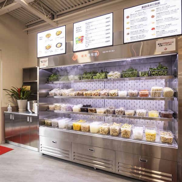 赤いカウンター横には、30種類以上の色とりどりな食材が並んでいます♪トングとボウルを持って、自分で好きな食材を選んでとることができるのが当店の特徴です！