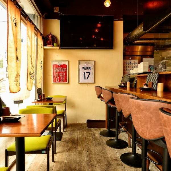 伝統的な焼き鳥店の情緒を残しつつ、ヴィンテージ感のあるポスターやスポットライトがカフェのようなお洒落さを演出しています。全面ガラス張りの開放的な入り口からは外の景色が見え、夜には温かい灯りが漏れる居心地の良い空間に。ユニフォームが飾られるなど、オーナーの個性が光るアットホームな一軒です。