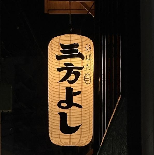 「炉ばた 三方よし」へようこそ！ 当店は、伝統と現代美が響き合う和モダンな空間です。 黒タイルに映える大きな提灯の下で、特別なひとときを過ごしませんか？ 皆様のご来店を心よりお待ちしております。